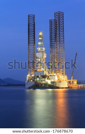 Jack up oil drilling rig in the shipyard for maintenance at sunset time Jack up oil drilling rig in the shipyard for maintenance at sunset time