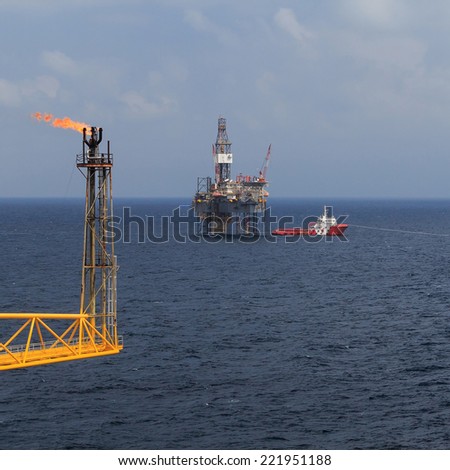Jack up drilling rig, flare boom, and crew boat in the middle of the sea
