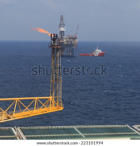 Jack up drilling rig, flare boom, and crew boat in the middle of the sea