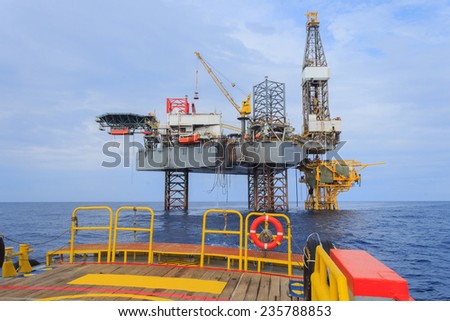 Offshore Jack Up Drilling Rig Over The Production Platform in The Middle of The Sea - View from Crew Boat