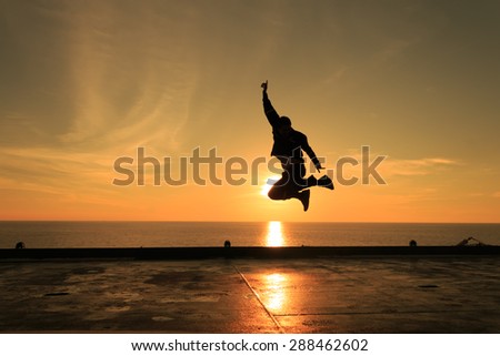 Man jumping against beautiful sunset. Freedom and enjoyment concept.