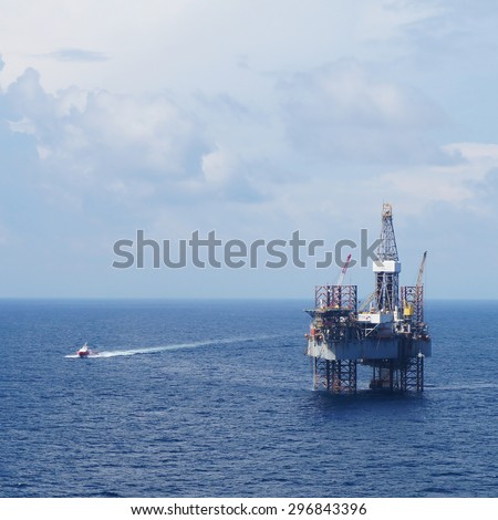 Jack up drilling rig and crew boat in the middle of the sea