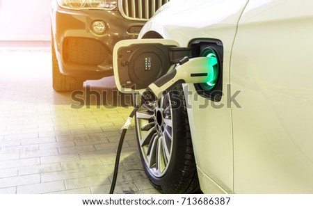 Power supply connect to electric car for add charge to the battery.  Charging re technology industry transport  which are the future of the Automobile.