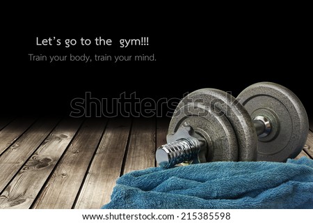 a dumbbell and a towel is on the wooden floor