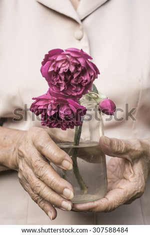 an old woman is holding wilt roses represent to time and health