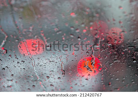 Rain drop on car glass and blur bokeh of tail light of car in a street