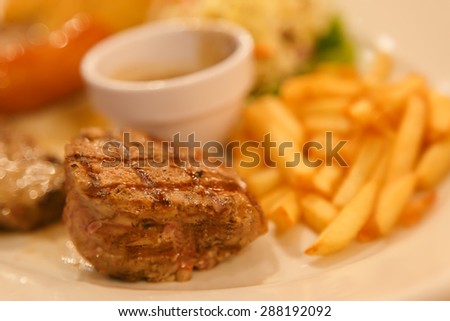 Meat or pork steak and salad in white plate with french fries, sauce,cup, sausage, german