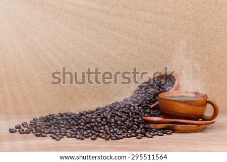 Coffee beans and wooden cup of coffee  with steam are on wooden background  for morning drink