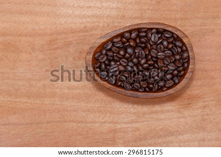 Coffee beans in wood cup are on wood floor  in the morning, top view