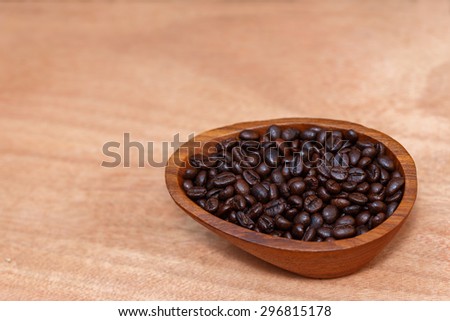 Coffee beans in wood cup are on wood floor  in the morning, top view