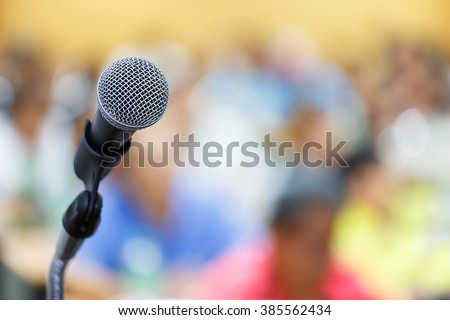 Microphone close up shot in seminar or meeting room with people in blur focus for copy space