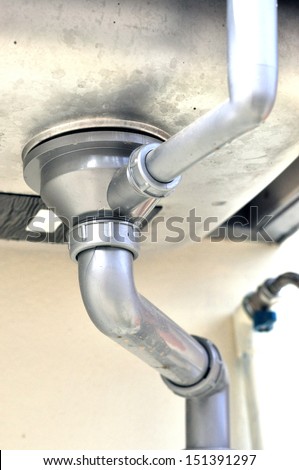 Metal sink siphon and drain in bathroom