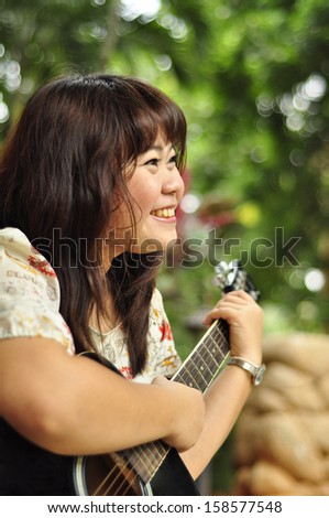 Asian woman with guitar in garden