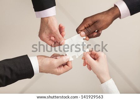 Closeup Of Businesspeople About To Put Four Puzzle Pieces Together. Top View. Close Up