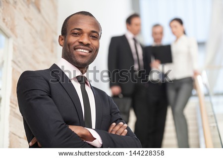Smiling businessman with his colleagues in background