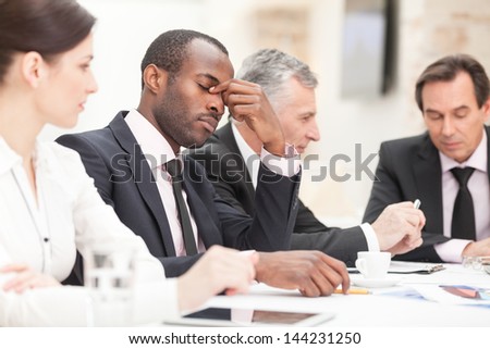 Portrait of a tired young business man bored during meeting