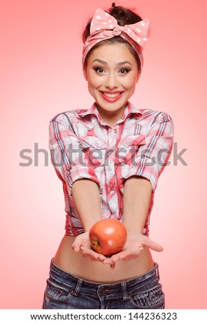 It's for you! Sexy young pin-up girl stretching out her hands holding an apple