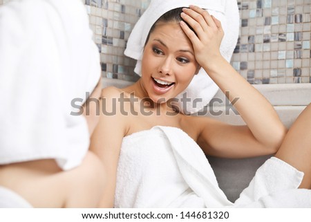 Two beautiful laughing females sitting and talking in Turkish sauna