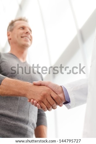 Thank you, doctor! Low angle view of thankful patient shaking the doctors hand