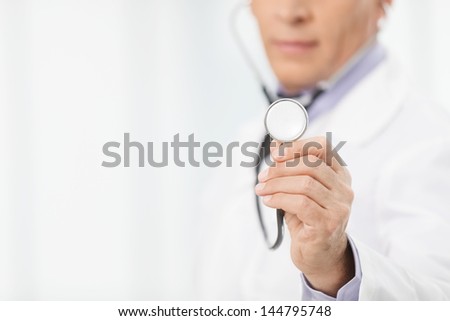 Doctor with stethoscope. Cropped image of mature doctor holding a stethoscope in his outstretched hand