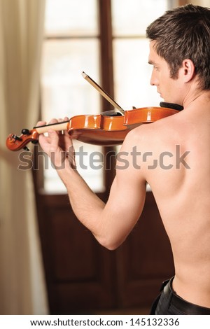 Playing with passion. Rear view of young men with naked torso playing the violin