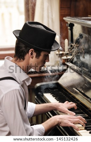 He got his own technique. Profile of handsome young men playing piano and smoking cigarette