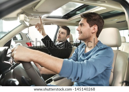 This model comes with added features Handsome young salesman showing all the car features to the customer This model comes with added features Handsome young salesman showing all the car features to the customer