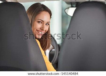 Are you ready to go? Attractive young woman sitting at the front seat of the car looking at camera