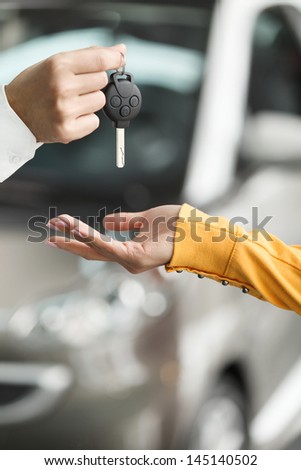She has made a right choise. Close-up shoot of the car salesman hand giving the key to female owner