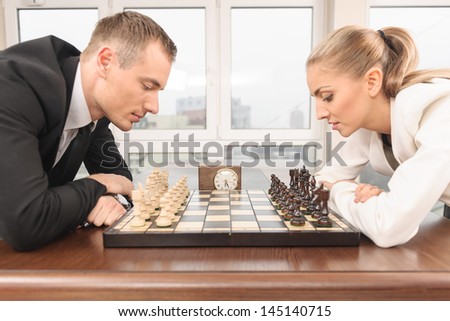 Man and woman playing chess at office