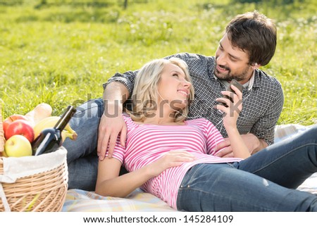 Listening to the music together. Loving young couple listening to the music on picnic together