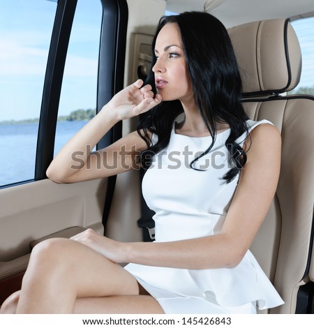 A gorgeous young Caucasian woman in a white dress looking through the car window