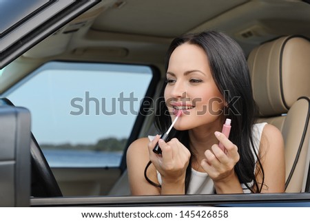 A beautiful young Caucasian woman doing make-up on the front seat of the car