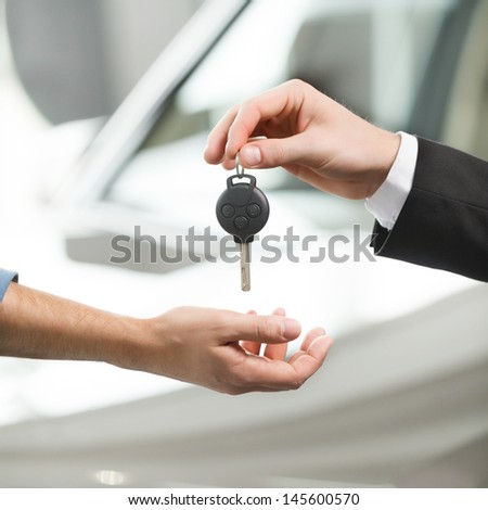 Drive Carefully! Close-Up Shoot Of The Car Salesman Hand Giving A Key To The Owner