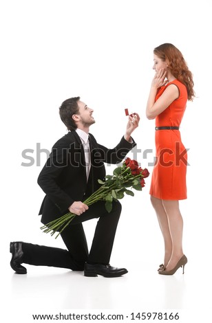 Young man in full suit standing on one knee and making a proposal to his girlfriend against white background Young man in full suit standing on one knee and making a proposal to his girlfriend against white background