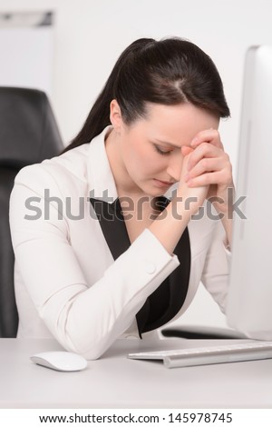 Bad day at office. Depressed middle-aged businesswoman sitting at her working place with her eyes closed and holding the head in hands