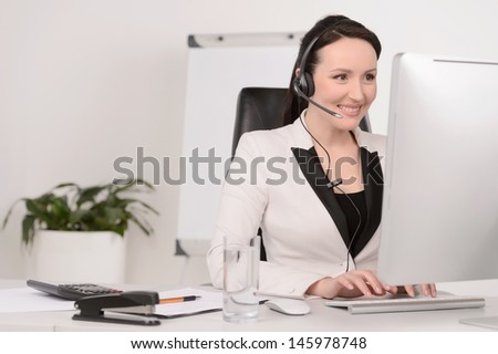 Customer service representative at work. Beautiful middle-aged customer service representative typing something on computer and smiling