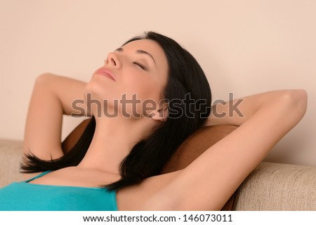 Women relaxing on the couch. Portrait of young women relaxing on the couch with her eyes closed and head in hands