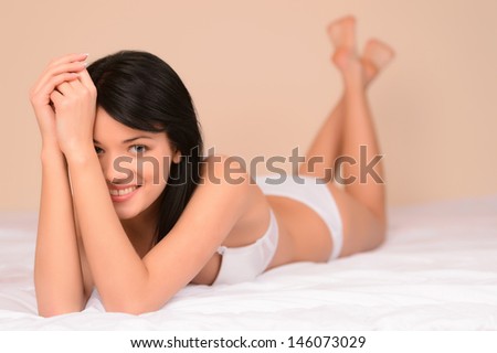 Shy and beautiful. Beautiful young woman lying on the sofa and looking at camera