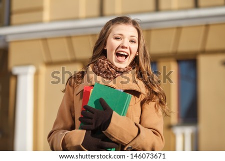Happy student. Happy young women holding the books and laughing at camera while standing outdoors