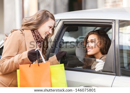 Friends meeting in town. Two female friends meet each other on the street while one of them sitting on the back seat of a car