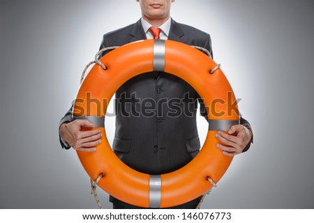 Life buoy for your business. Businessman holding a life belt while isolated on gray