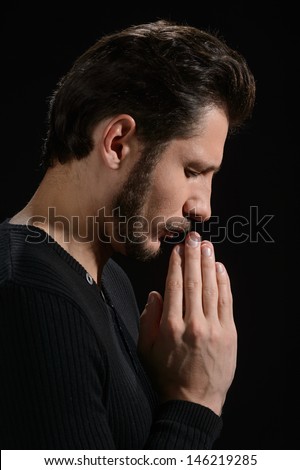 The power of prayer. Side view of bearded man praying and holding his hands clasped