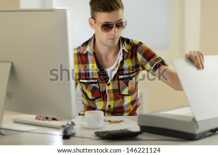 Creative man. Handsome young men in sunglasses sitting at his working place and using scanner