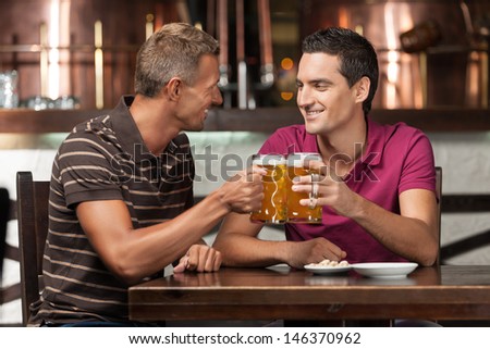 Old friends meeting. Two happy friends drinking beer at the pub