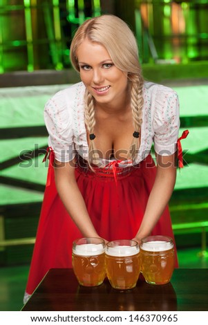 Women in traditional German clothing. Beautiful young women in traditional German costume holding the beer mugs and smiling at camera