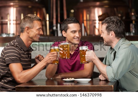 Meeting At The Pub. Three Happy Friends Drinking Beer At The Pub