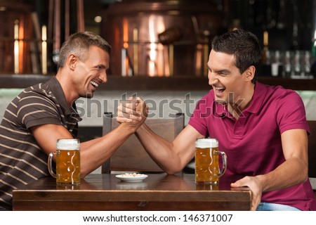 Having fun at the bar. Two friends drinking beer and having fun at the pub