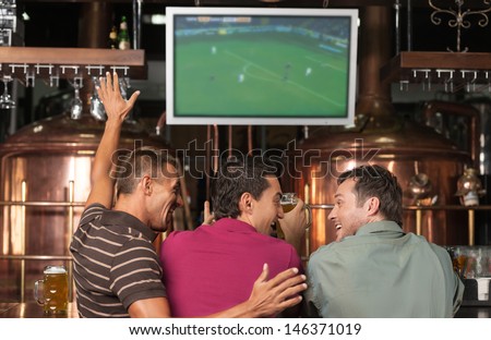 Happy Soccer Fans. Three Happy Soccer Fans Watching A Game At The Pub