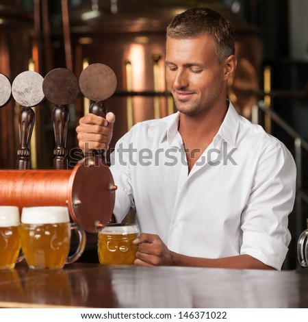 Serving The Best Beer In Town. Handsome Bartender In White Shirt Serving Beer